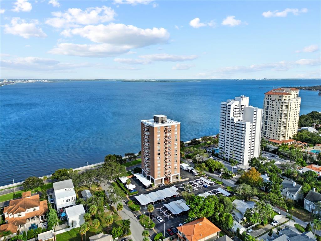 An aerial view shows high-rise apartment buildings situated along a large body of water — 4015 BAYSHORE BOULEVARD UNIT 7C, TAMPA, FL
