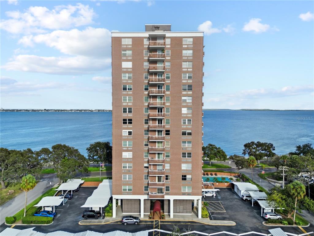 An aerial view of a tall brick apartment building with balconies facing a large body of water — 4015 BAYSHORE BOULEVARD UNIT 7C, TAMPA, FL