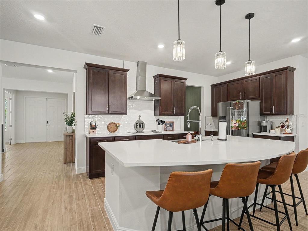 A kitchen features dark wood cabinets, white countertops, a large island, and three pendant lights — 7474 SEA MANATEE STREET, PARRISH, FL