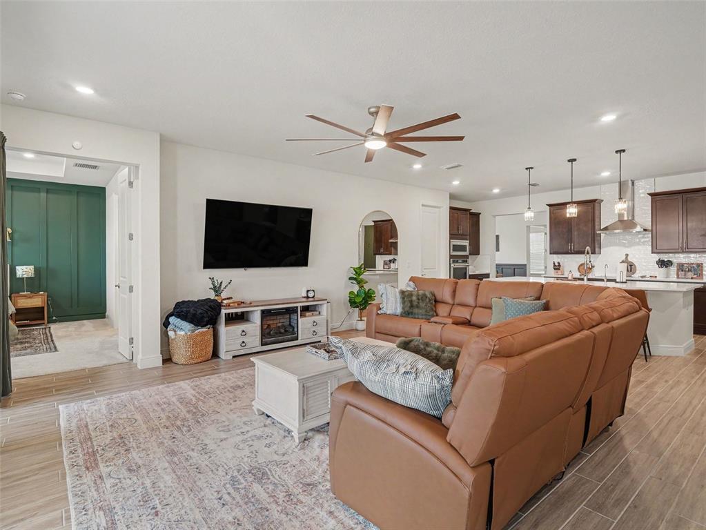 A living room with a brown leather sectional, a television, and an open kitchen — 7474 SEA MANATEE STREET, PARRISH, FL