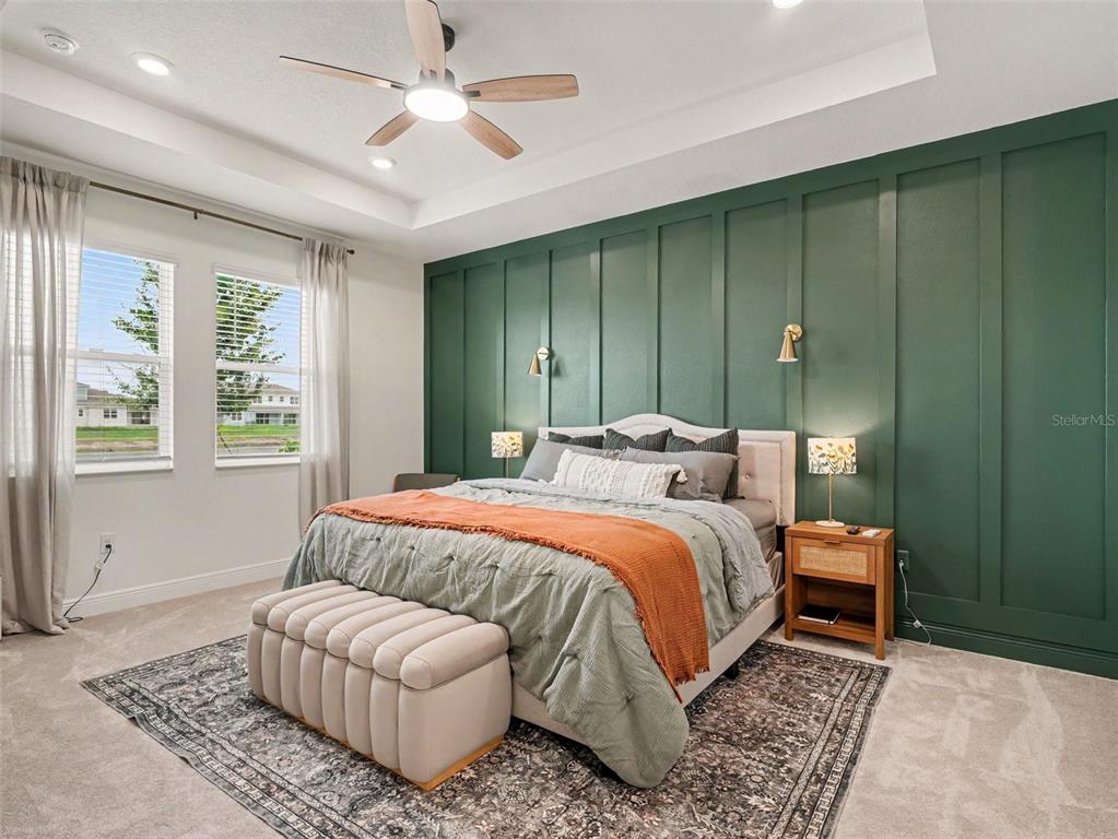 A bedroom features a green board-and-batten accent wall, a tray ceiling, and a patterned rug — 7474 SEA MANATEE STREET, PARRISH, FL