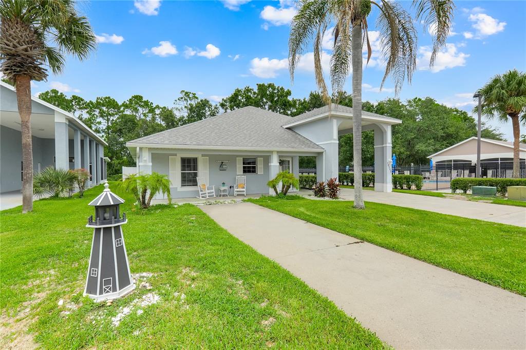 A light blue single-story house features a concrete walkway, a lighthouse ornament, and palm trees — 16345 CITRUS PARKWAY, CLERMONT, FL