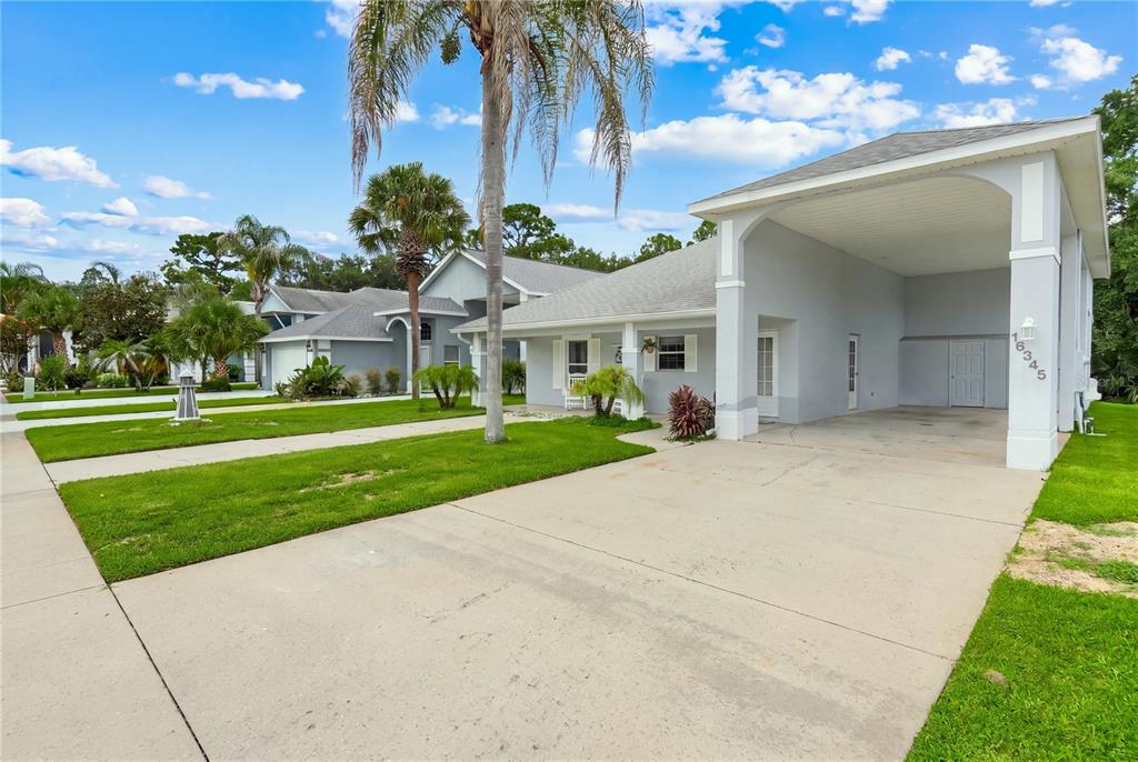 A light gray single-story house features a large covered carport and a front lawn — 16345 CITRUS PARKWAY, CLERMONT, FL