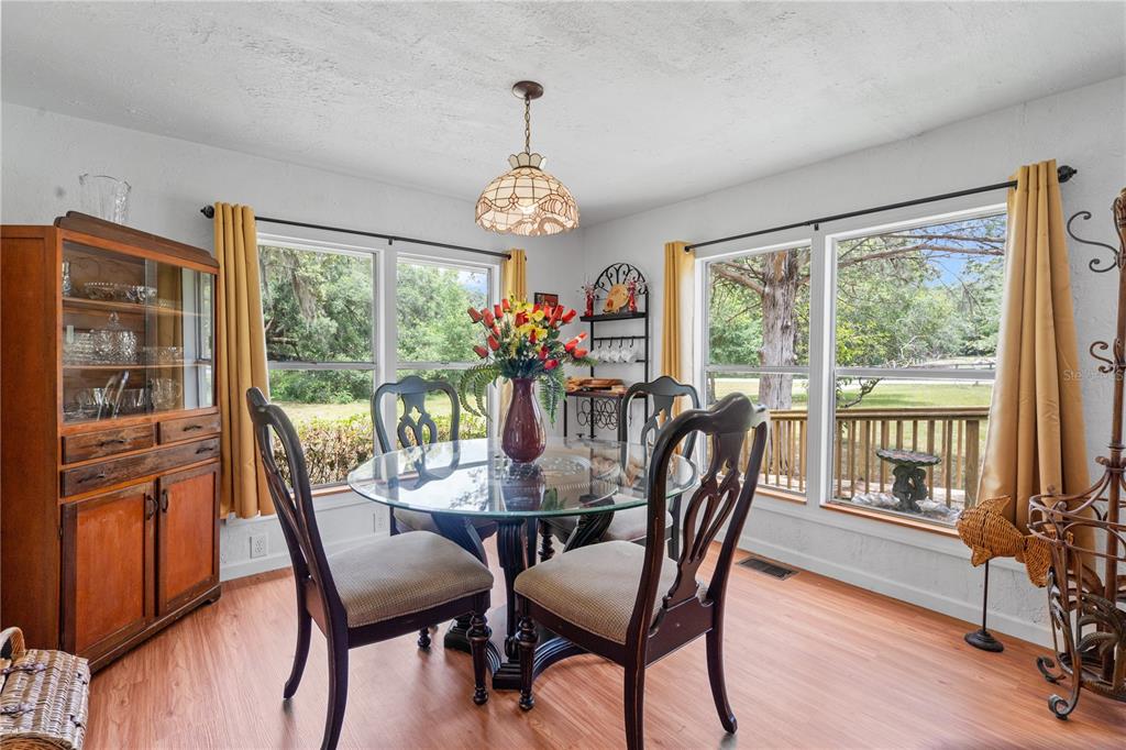 A dining room features a glass-topped table, wooden chairs, a hutch, and large windows — 6850 SE 192ND COURT, MORRISTON, FL