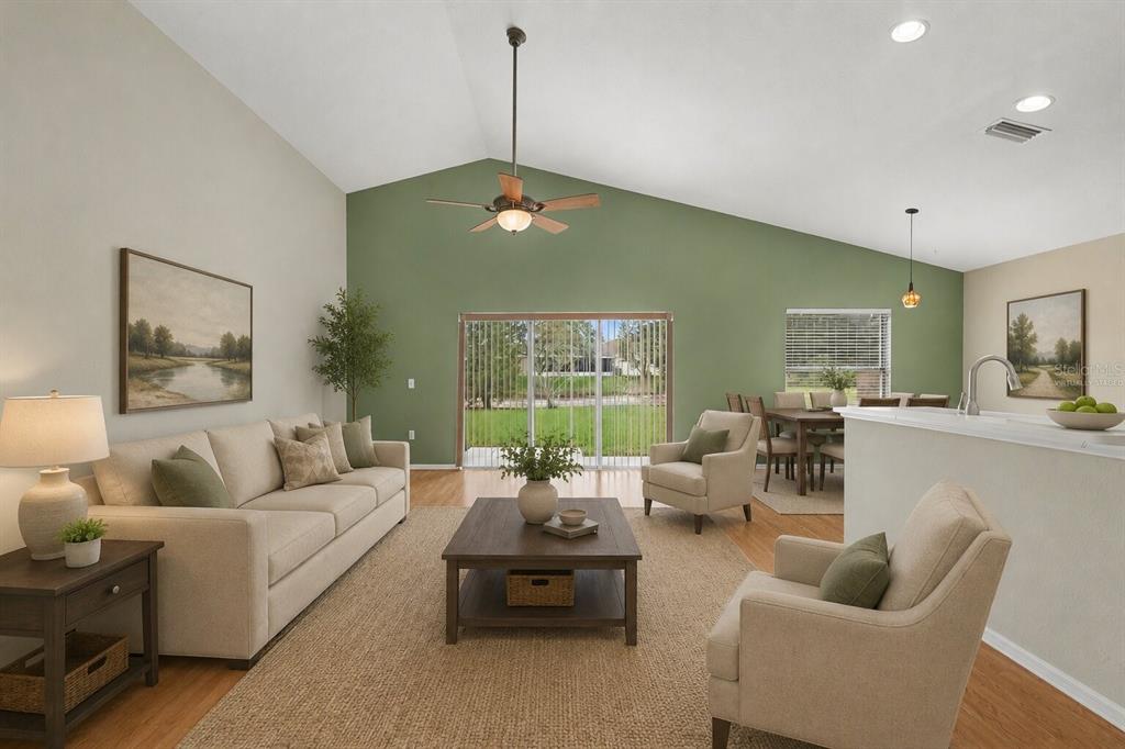 A living room with vaulted ceilings, a green accent wall, and a sliding glass door — 9407 CYPRESS HARBOR DRIVE, GIBSONTON, FL