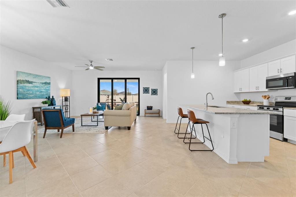 An open-concept kitchen and living area features white cabinets, granite countertops, and tile flooring — 1536 SADDLEWOOD CIRCLE, PORT CHARLOTTE, FL