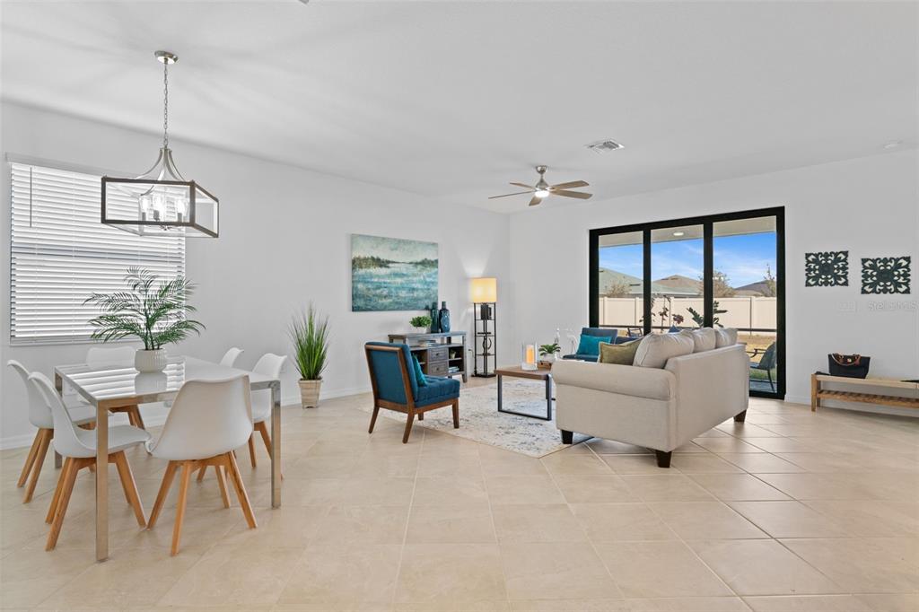 An open-concept living and dining area features tile flooring, white walls, and sliding glass doors — 1536 SADDLEWOOD CIRCLE, PORT CHARLOTTE, FL