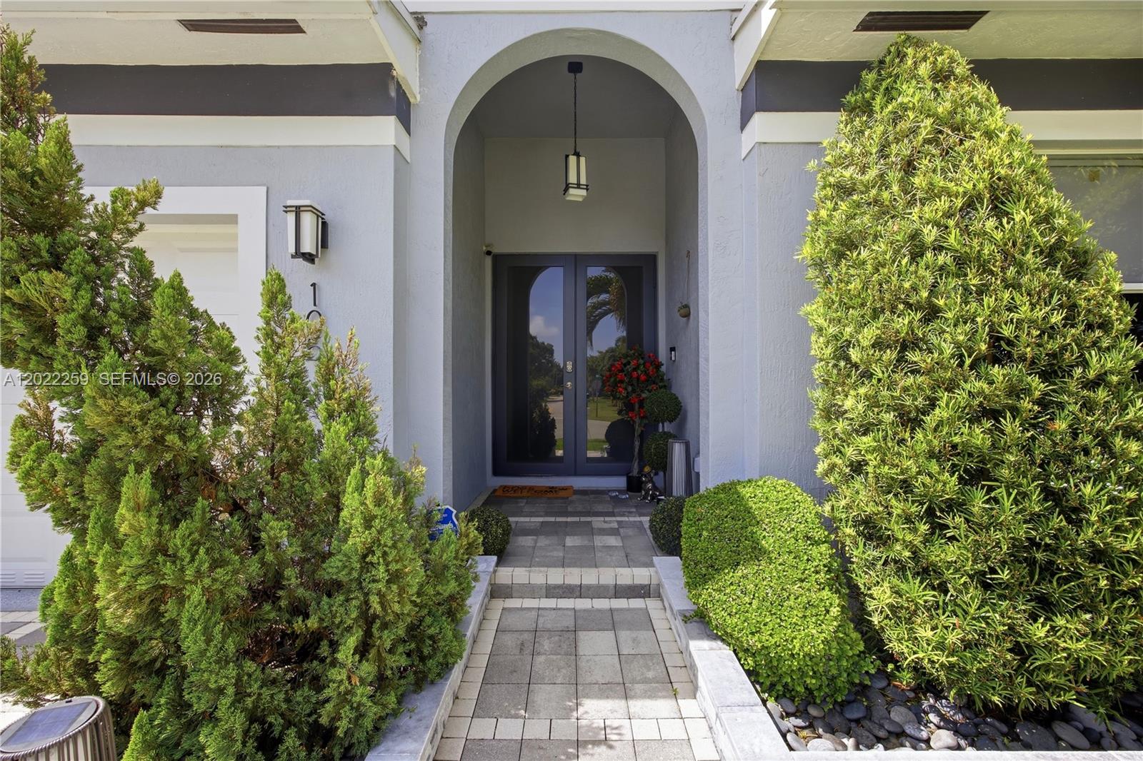 A paved walkway leads to a gray arched entryway with double glass front doors — 105 NE 28th Ct, Wilton Manors FL 33334, WILTON MANORS, FL