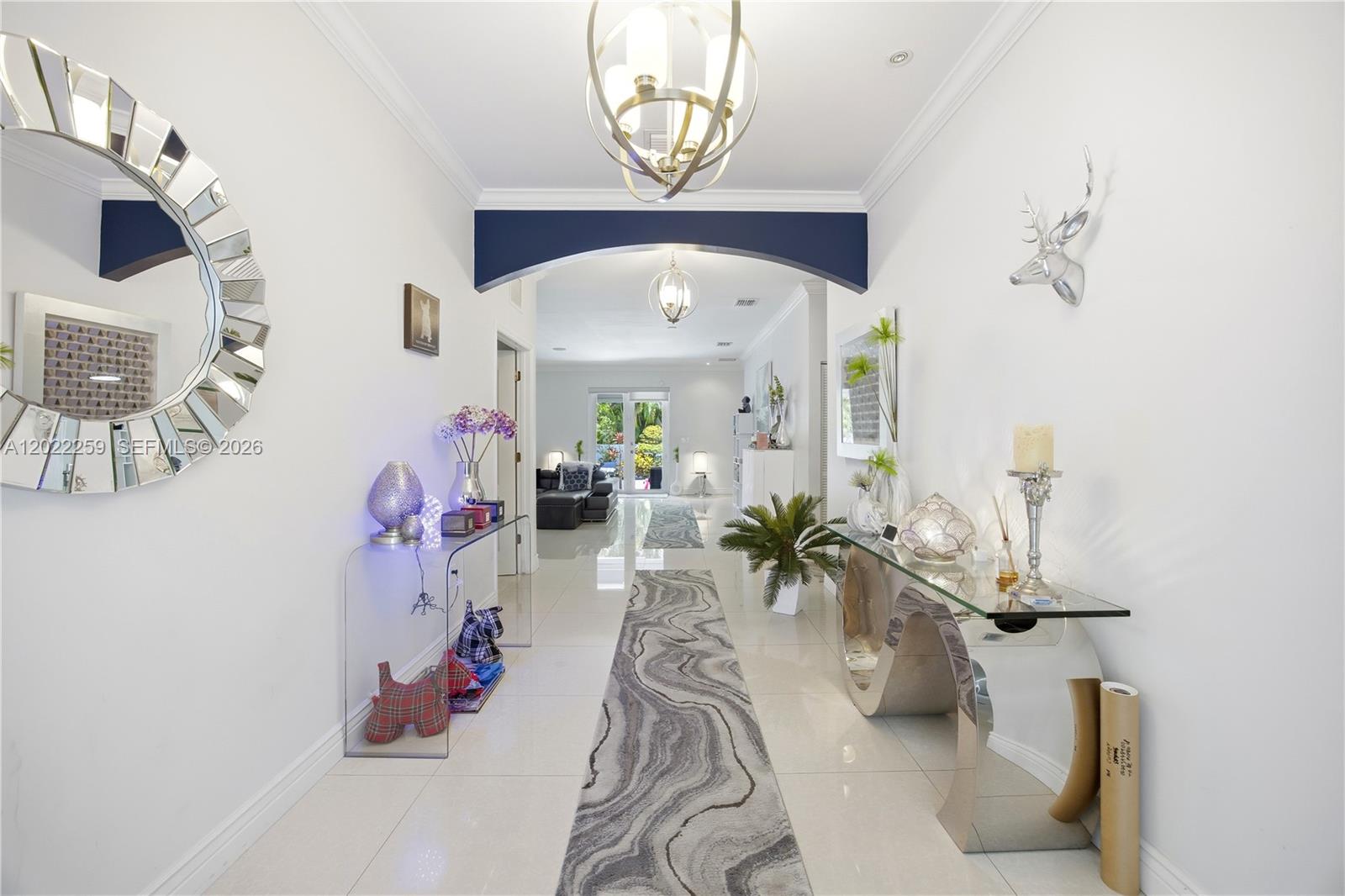 A bright, tiled entryway features two glass console tables, a circular mirror, and a runner rug — 105 NE 28th Ct, Wilton Manors FL 33334, WILTON MANORS, FL