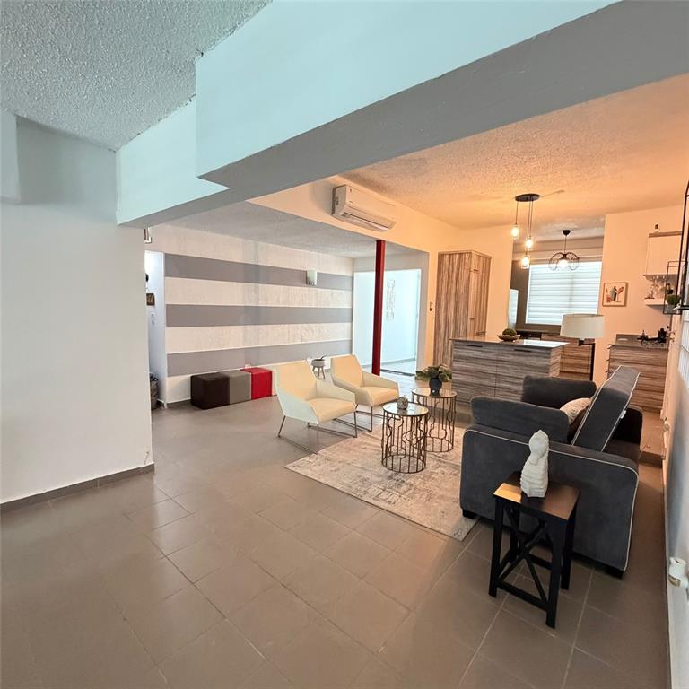 An open-concept living room features a striped accent wall, tile flooring, and a kitchen island — Marullo 5 DORADO DEL MAR UNIT O5, DORADO, PR