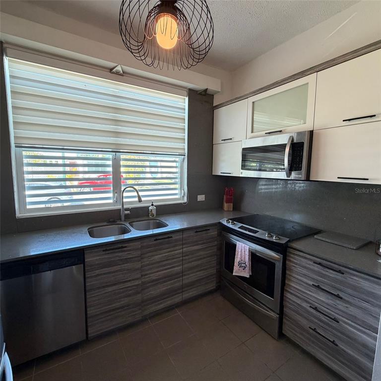 A kitchen features grey wood-grain cabinets, stainless steel appliances, and a large window with blinds — Marullo 5 DORADO DEL MAR UNIT O5, DORADO, PR