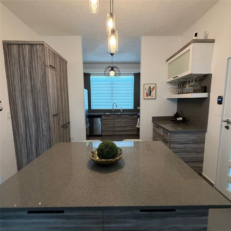 A modern kitchen features a large gray island, wood-grain cabinetry, and a bar area — Marullo 5 DORADO DEL MAR UNIT O5, DORADO, PR