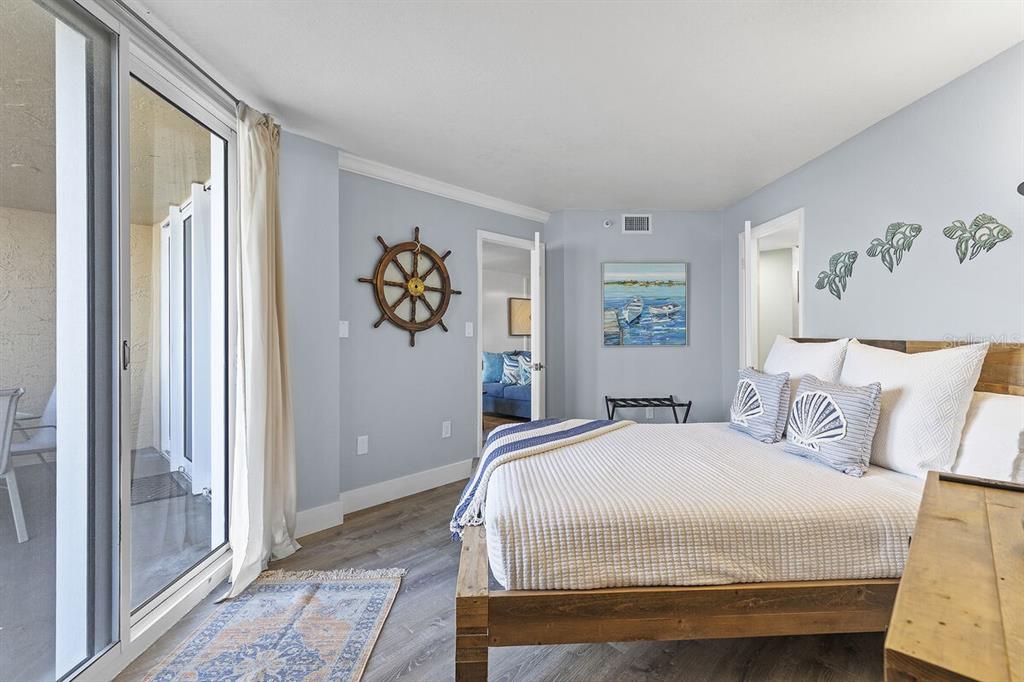 A bedroom with light blue walls, a wooden bed frame, and a sliding glass door — 421 S ATLANTIC AVENUE UNIT 103, NEW SMYRNA BEACH, FL