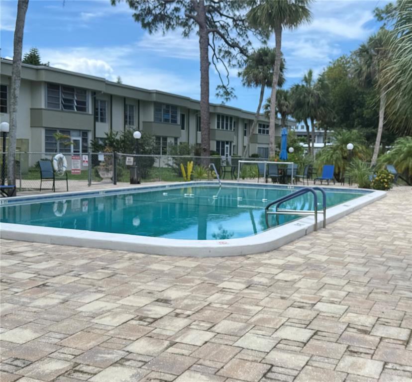 A rectangular swimming pool with a paved deck sits in front of a multi-story apartment building — 21300 BRINSON AVENUE UNIT 101, PORT CHARLOTTE, FL