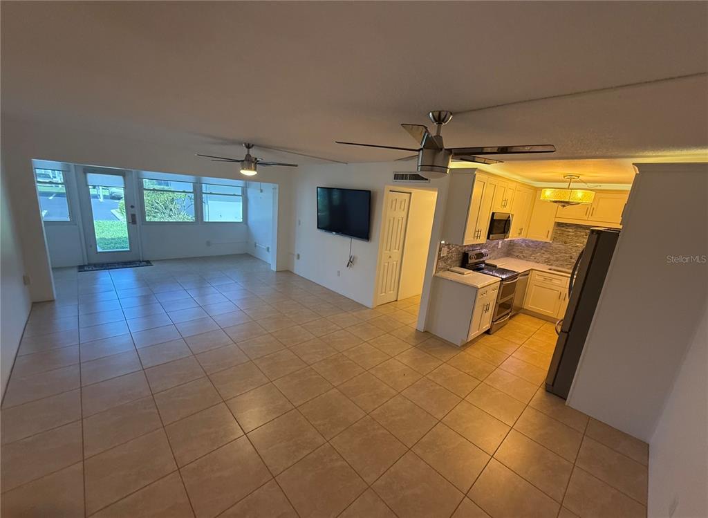 An open-concept living area with tile flooring, a kitchen, and a sunroom with windows — 21300 BRINSON AVENUE UNIT 101, PORT CHARLOTTE, FL