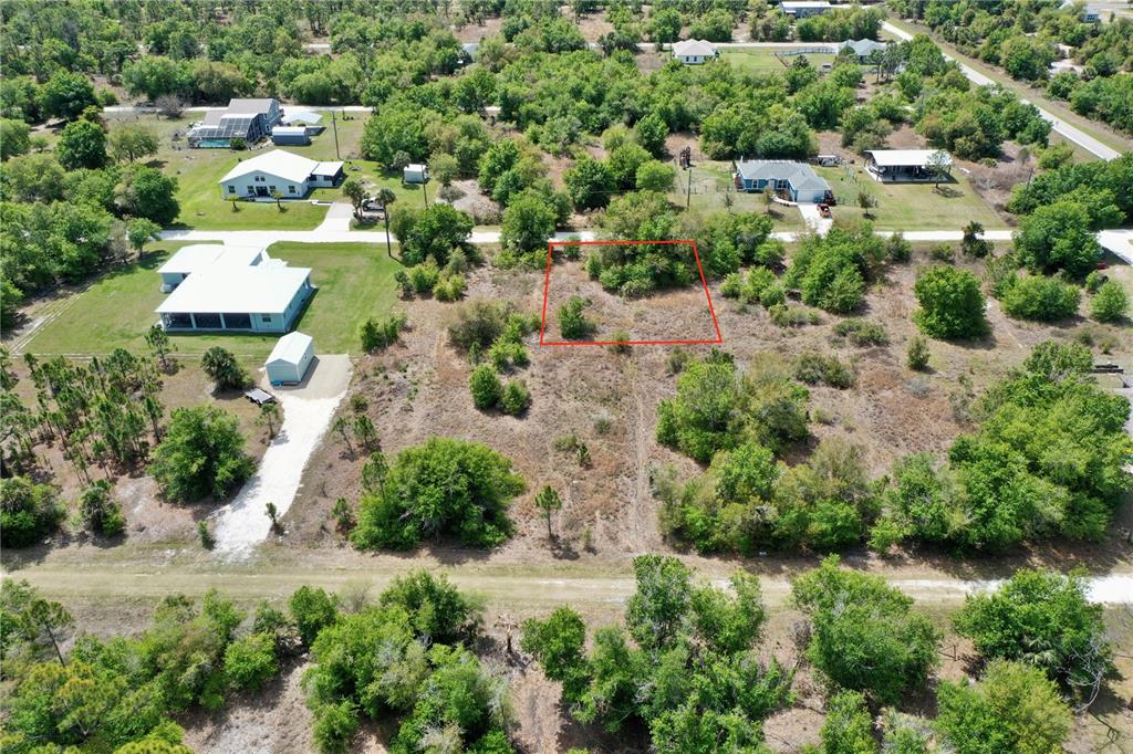 An aerial view shows a vacant, partially wooded residential lot outlined in red — 27054 MINGO DRIVE, PUNTA GORDA, FL