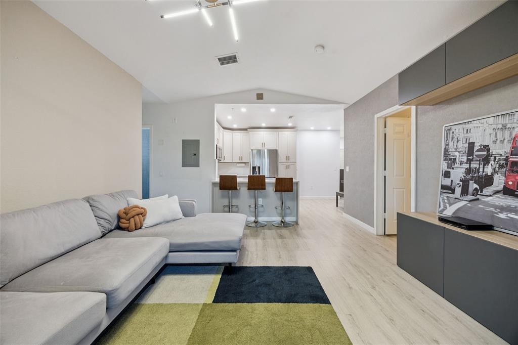 A living room with a gray sectional sofa, a colorful rug, and an open kitchen — 5550 E MICHIGAN STREET UNIT 2321, ORLANDO, FL