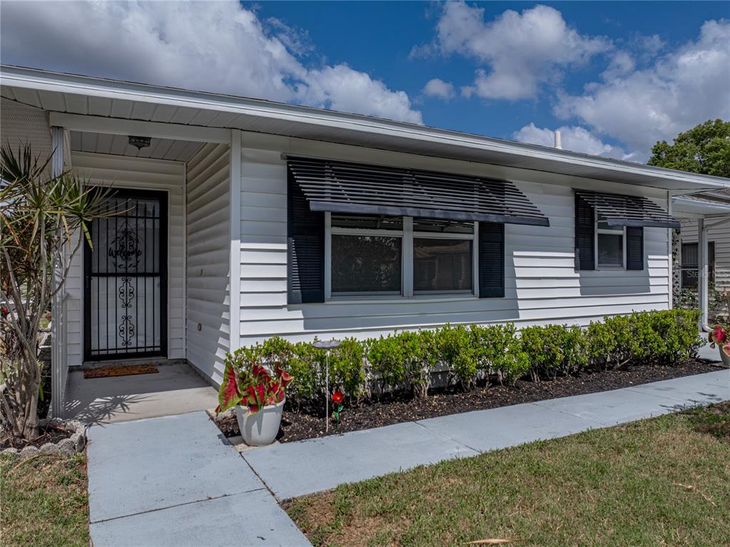 The exterior of a white, single-story house features a front door with a security gate — 4965 GOLDENVIEW LANE, LAKELAND, FL