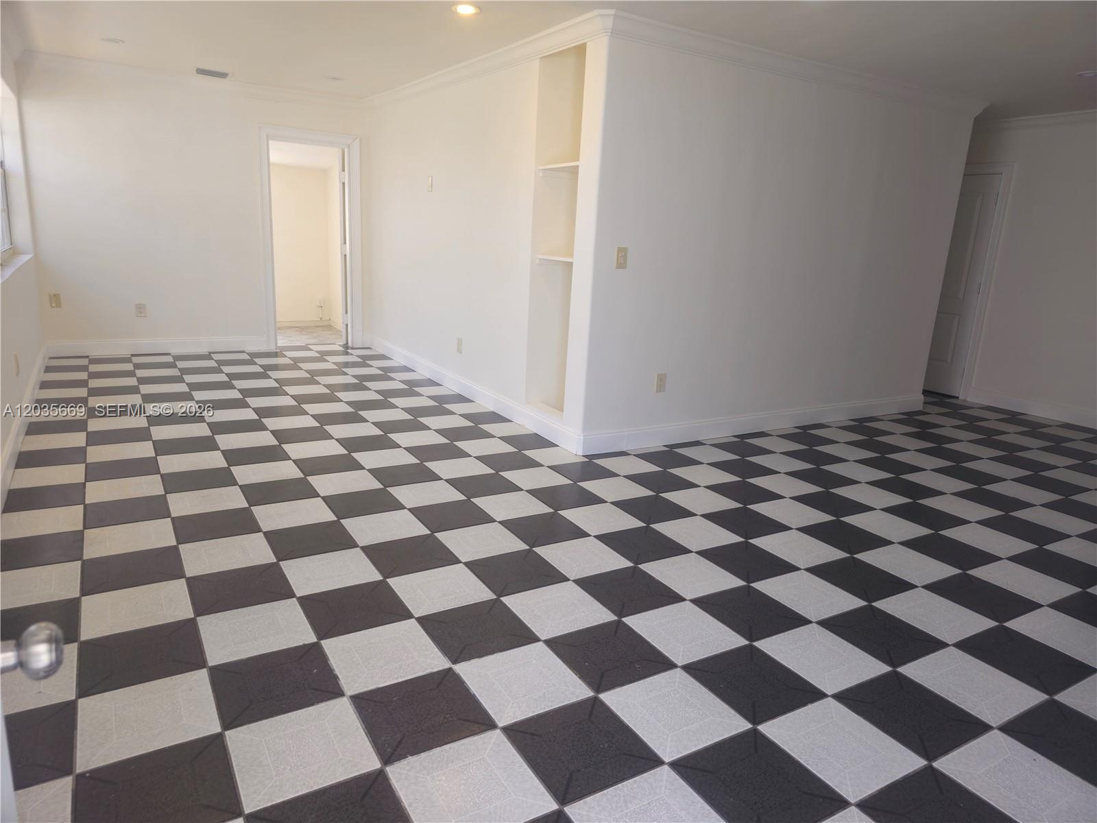 An empty room features white walls, built-in shelving, and a black-and-white checkered tile floor — 2521 NW 13th Ave # 2521, Miami FL 33142, MIAMI, FL