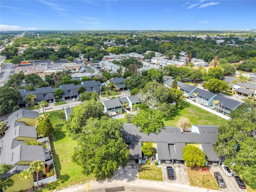 An aerial view shows multiple residential townhouse buildings surrounded by green lawns and mature trees — 7488 WHISPERWOOD DRIVE UNIT 28, WINTER PARK, FL