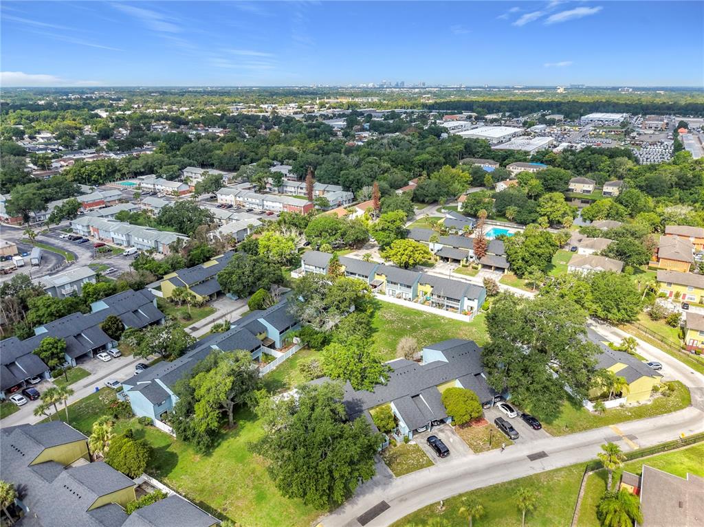 An aerial view shows a residential complex with multiple townhome buildings surrounded by green trees — 7488 WHISPERWOOD DRIVE UNIT 28, WINTER PARK, FL