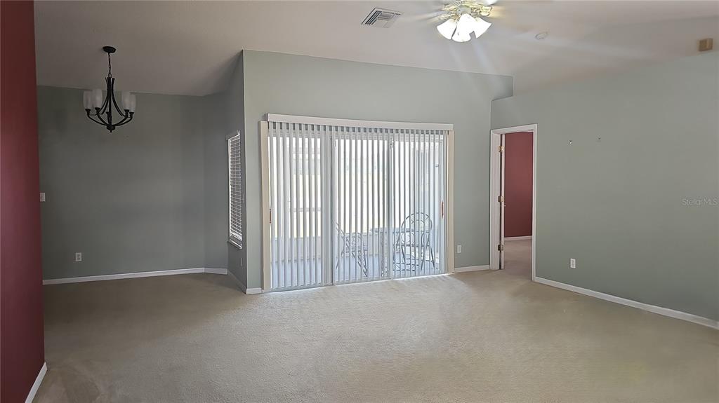 A living room with beige carpet, light green walls, a ceiling fan, and sliding glass doors — 4030 LAKE BLUFF DRIVE, MASCOTTE, FL