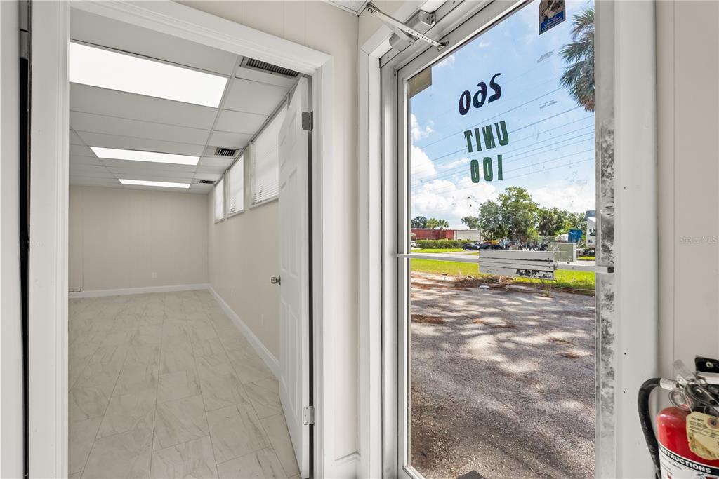 An empty office space with tile flooring and a glass door looking out to parking — 260 POWER COURT, SANFORD, FL