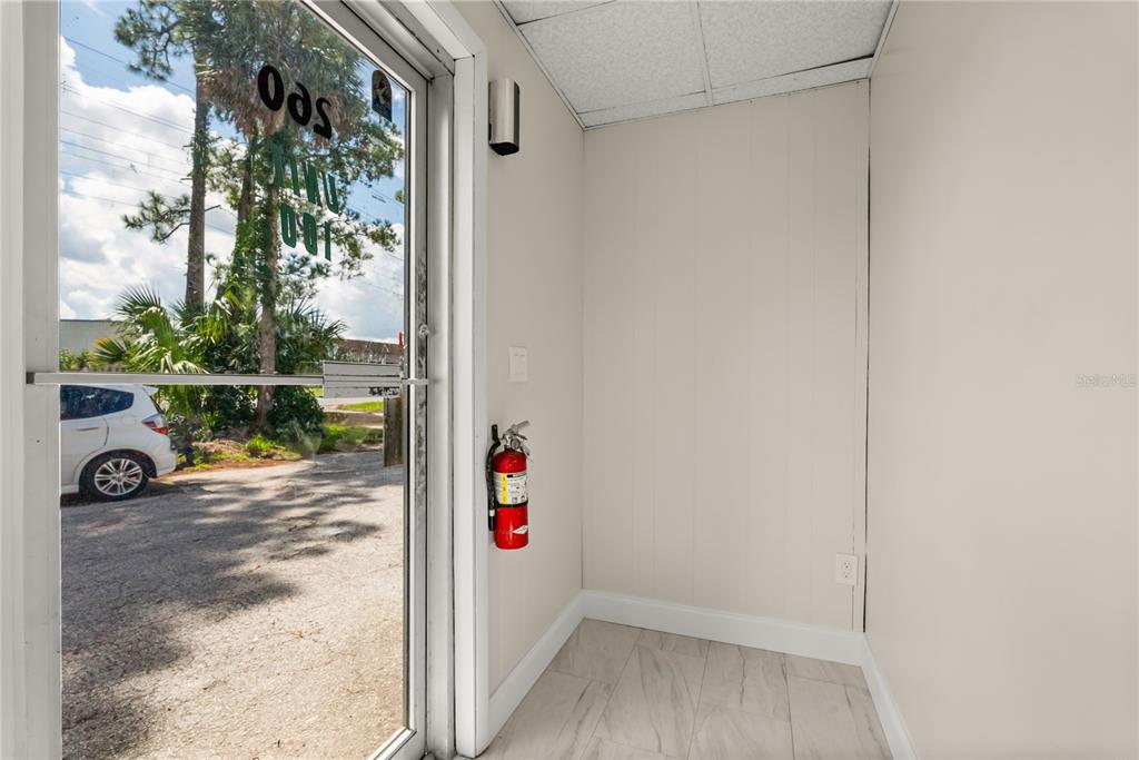 A small entryway features a glass door, a fire extinguisher, and light-colored tile flooring — 260 POWER COURT, SANFORD, FL