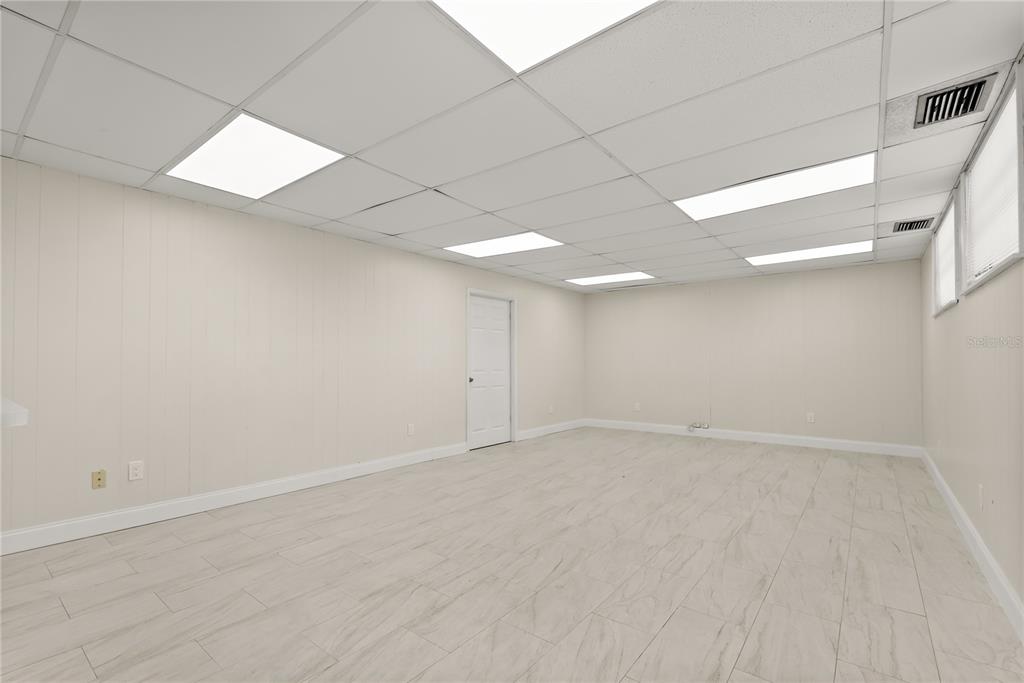 An empty room with white paneled walls, a drop ceiling, and light-colored wood-look tile flooring — 260 POWER COURT, SANFORD, FL
