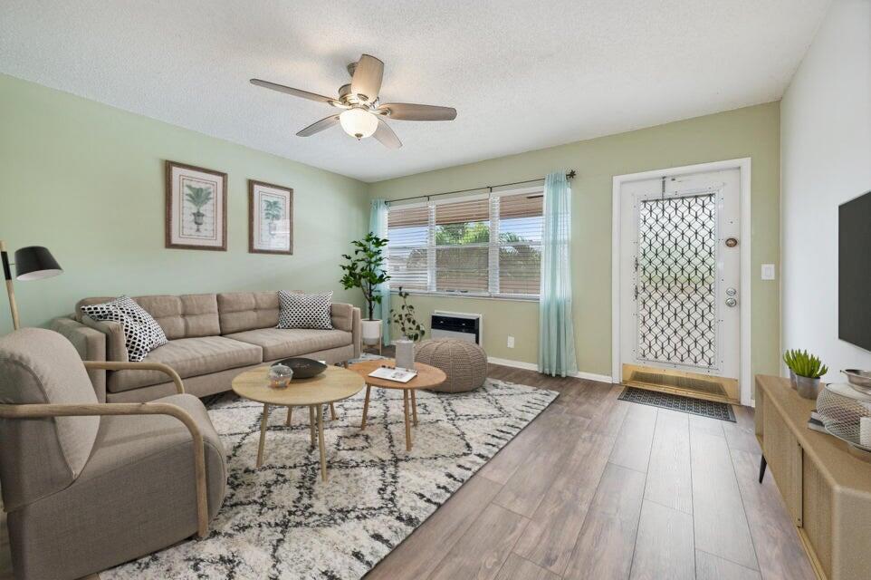 A living room features light green walls, a beige sofa, wood flooring, and a ceiling fan — 98 Ventnor E # 98, Deerfield Beach FL 33442, DEERFIELD BEACH, FL