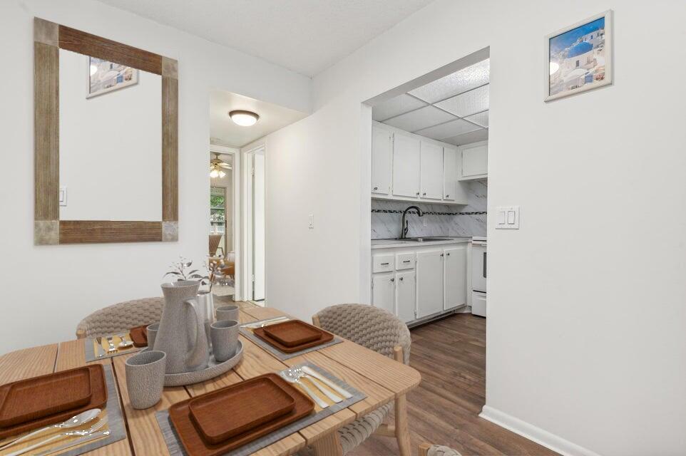 A dining area with a wooden table leads into a white kitchen with wood flooring — 98 Ventnor E # 98, Deerfield Beach FL 33442, DEERFIELD BEACH, FL