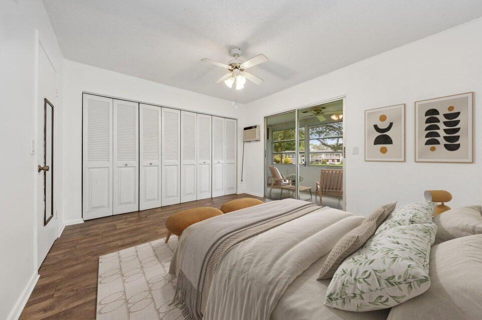 A bedroom with wood-look flooring, a large closet with white louvered doors, and sliding glass doors — 98 Ventnor E # 98, Deerfield Beach FL 33442, DEERFIELD BEACH, FL