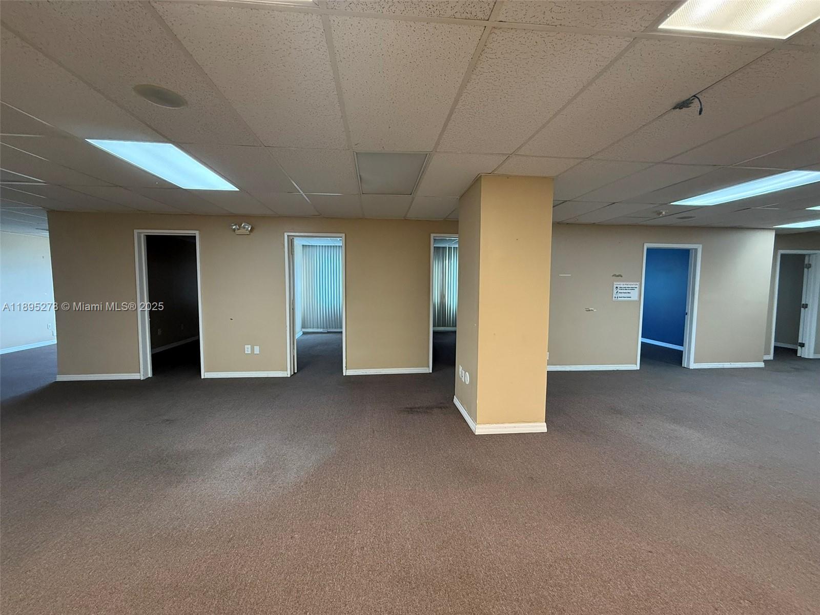 An office interior features beige walls, brown carpeting, a drop ceiling, and multiple doorways — 299 Alhambra Cir, Coral Gables FL 33134, CORAL GABLES, FL
