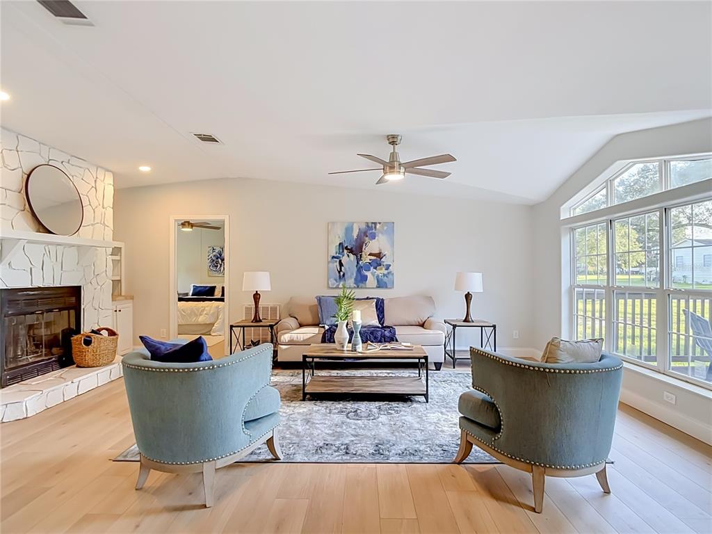 A living room features a stone fireplace, two blue armchairs, and a large window — 33124 JAMETTE ROAD, DADE CITY, FL