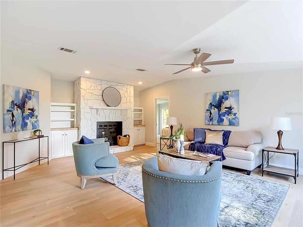 A living room features a white stone fireplace, two blue armchairs, and a beige sofa — 33124 JAMETTE ROAD, DADE CITY, FL