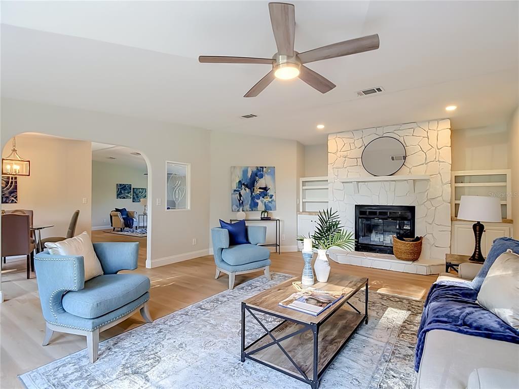 A living room features a white stone fireplace, light wood floors, and blue accent furniture — 33124 JAMETTE ROAD, DADE CITY, FL