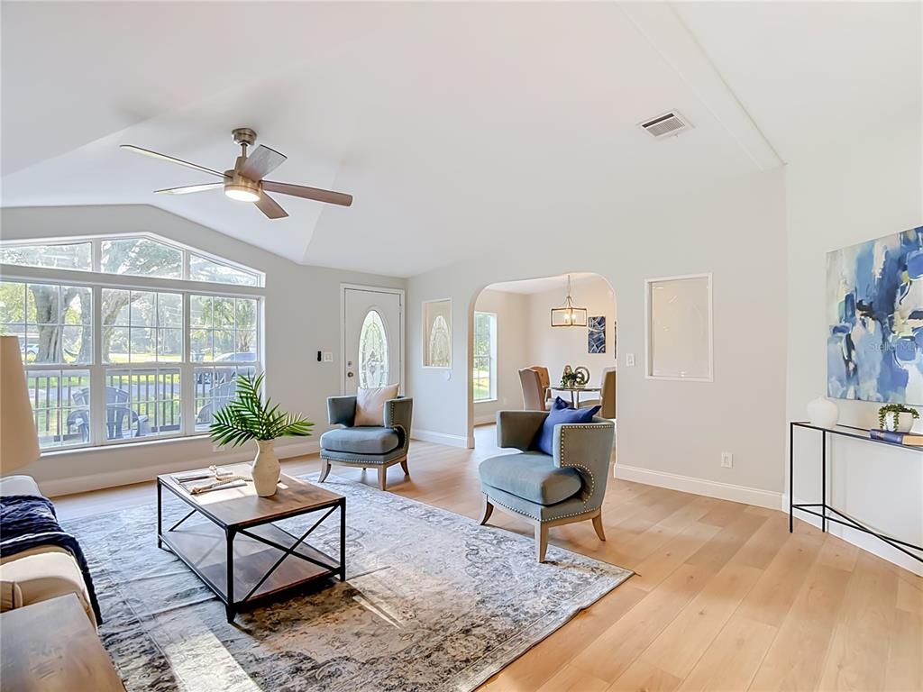 A bright living room features vaulted ceilings, light wood floors, and two blue armchairs — 33124 JAMETTE ROAD, DADE CITY, FL