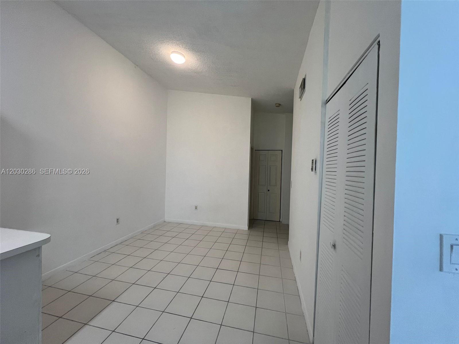 An empty room features white walls, a tiled floor, a ceiling light, and a closet — 15315 SW 76th Ter # 207, Miami FL 33193, MIAMI, FL