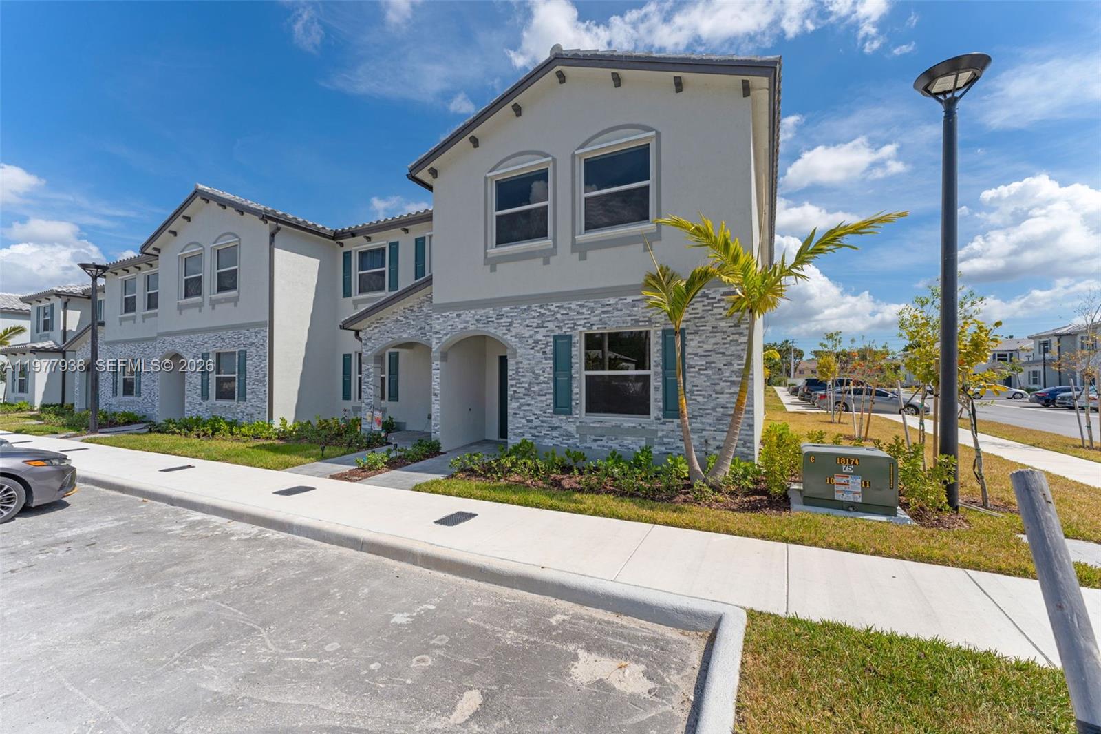 A two-story townhouse features a light-colored stucco facade with stone veneer accents and teal shutters — 191 SE 11th Ave, Florida City FL 33034, FLORIDA CITY, FL