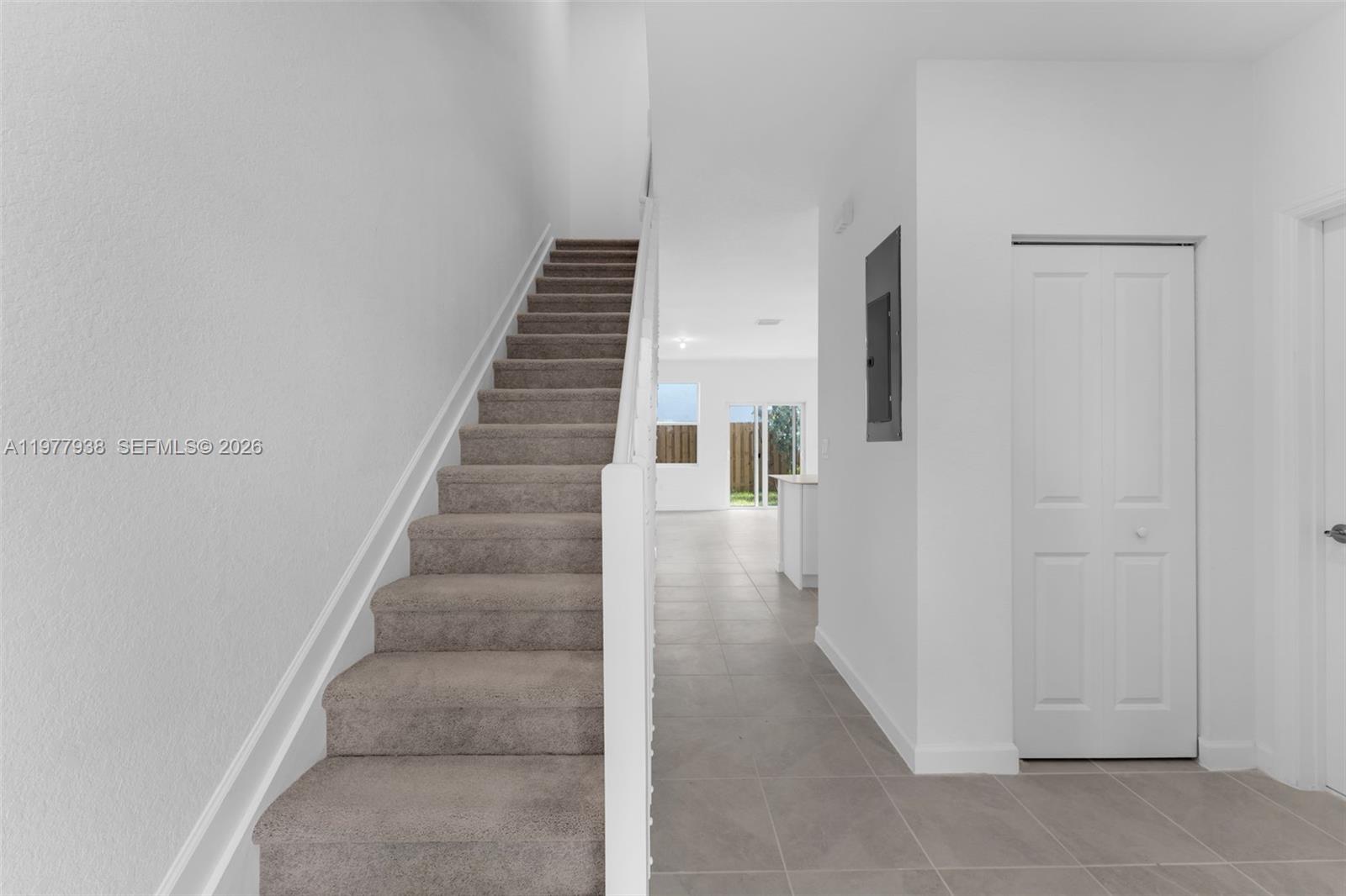 A carpeted staircase leads upward next to a tiled hallway with a closed white door — 191 SE 11th Ave, Florida City FL 33034, FLORIDA CITY, FL