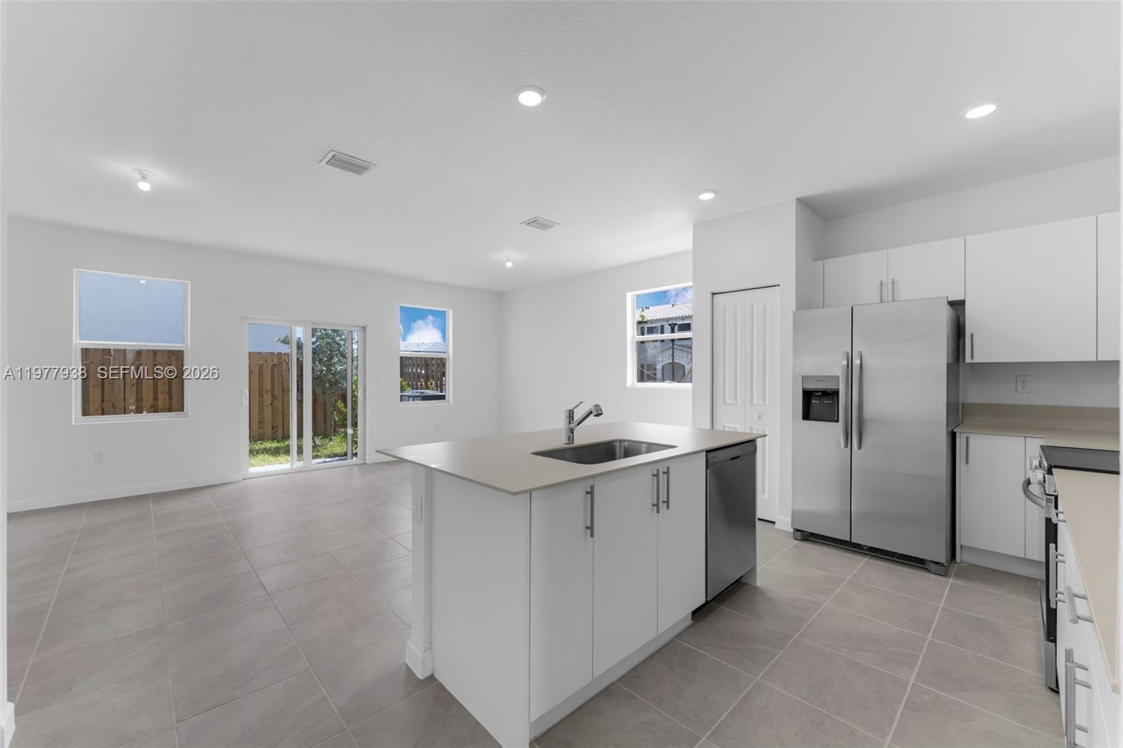 A modern kitchen features white cabinetry, stainless steel appliances, a center island, and tile flooring — 191 SE 11th Ave, Florida City FL 33034, FLORIDA CITY, FL