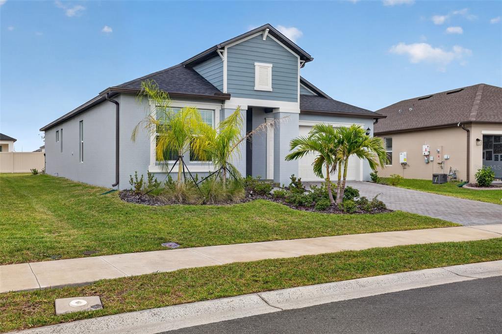 A single-story house with blue siding, a two-car garage, and palm trees in the front yard — 7542 117TH LANE E, PALMETTO, FL