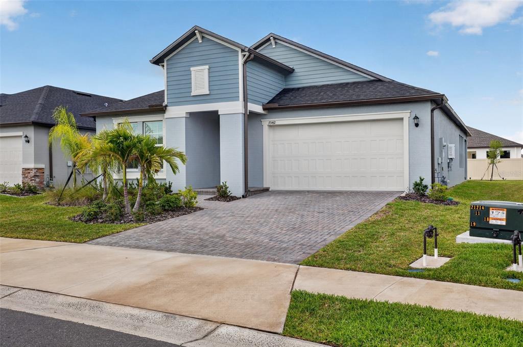A blue and gray single-story house with a paved driveway and a two-car garage — 7542 117TH LANE E, PALMETTO, FL