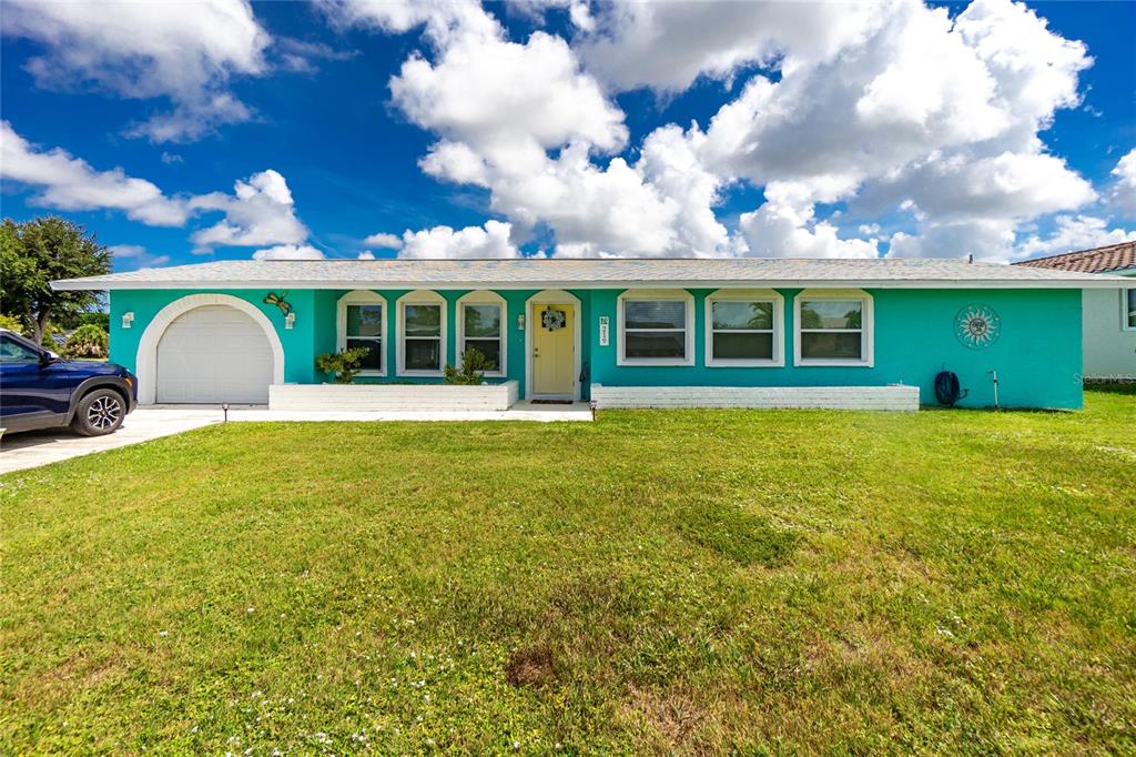 A single-story teal house with a garage, white trim, and a yellow front door — 219 CADDY ROAD, ROTONDA WEST, FL