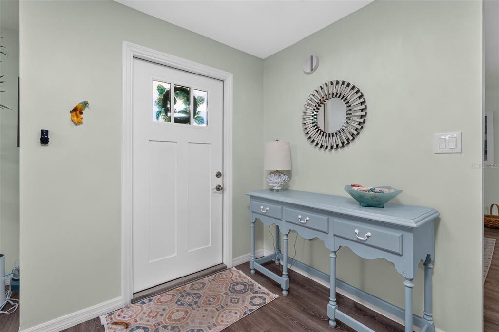 An entryway features a white front door, a blue console table, and a circular mirror — 219 CADDY ROAD, ROTONDA WEST, FL