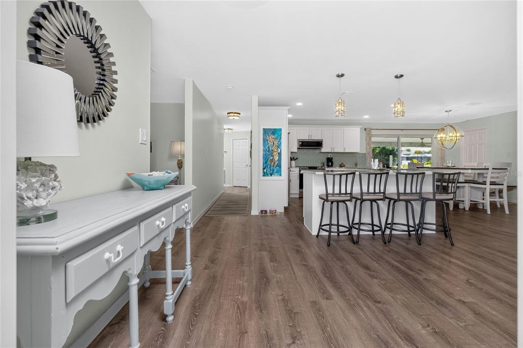 A view of an open-concept kitchen and dining area with wood-look flooring and white cabinetry — 219 CADDY ROAD, ROTONDA WEST, FL