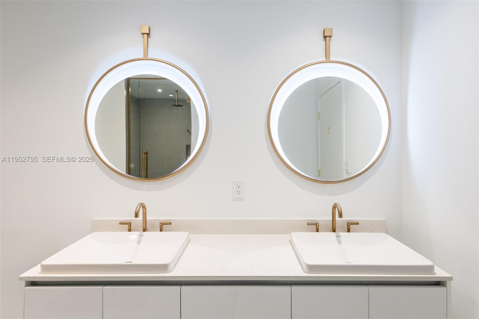 A modern bathroom features a double vanity with white sinks, gold faucets, and backlit mirrors — 2678 Tigertail Ave # 1707, Miami FL 33133, MIAMI, FL