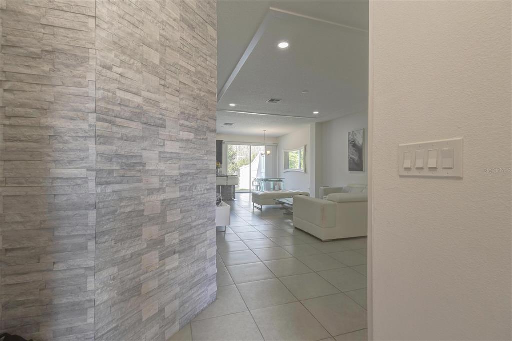 A view from a hallway into a living area featuring a stone accent wall — 2403 SEDGE GRASS WAY, ORLANDO, FL