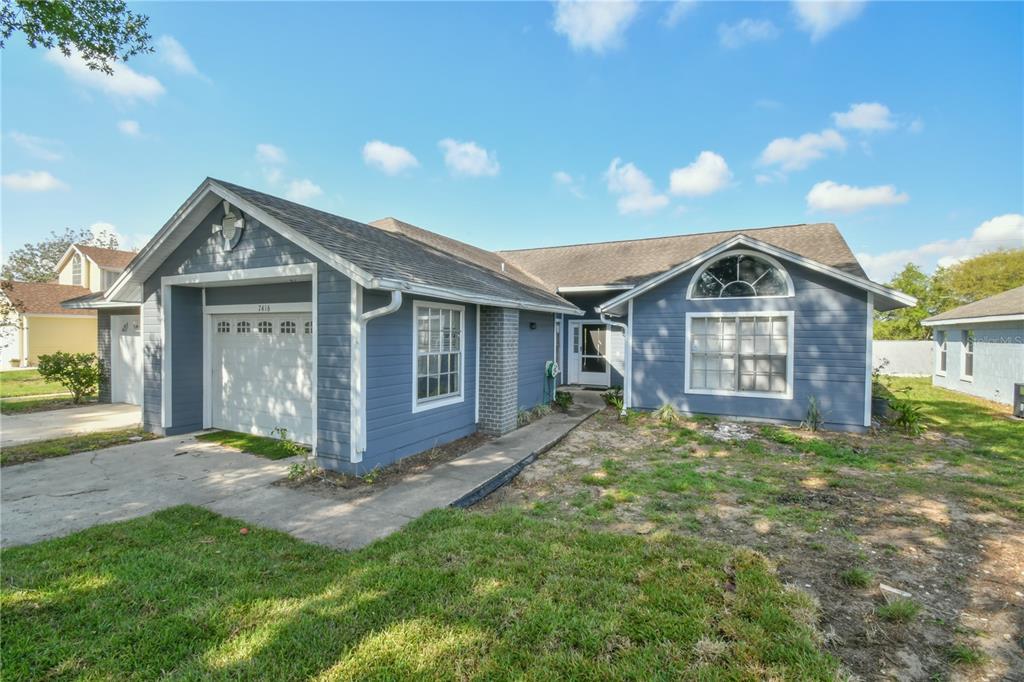 A blue-sided single-story house with a white garage door and a front-facing arched window — 7416 LITTLE POND COURT, ORLANDO, FL