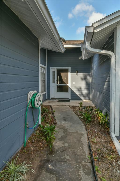 A concrete walkway leads to the front entrance of a house with blue siding — 7416 LITTLE POND COURT, ORLANDO, FL